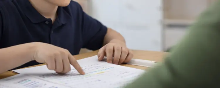 Child pointing at worksheet while working with a tutor