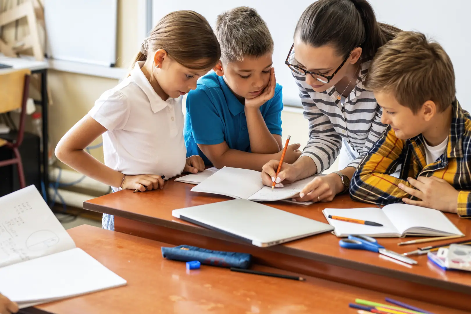 Pupils writing at a table in a small group lesson