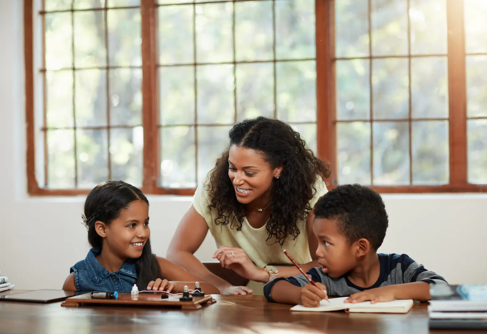 Tutor teaching two children at a table
