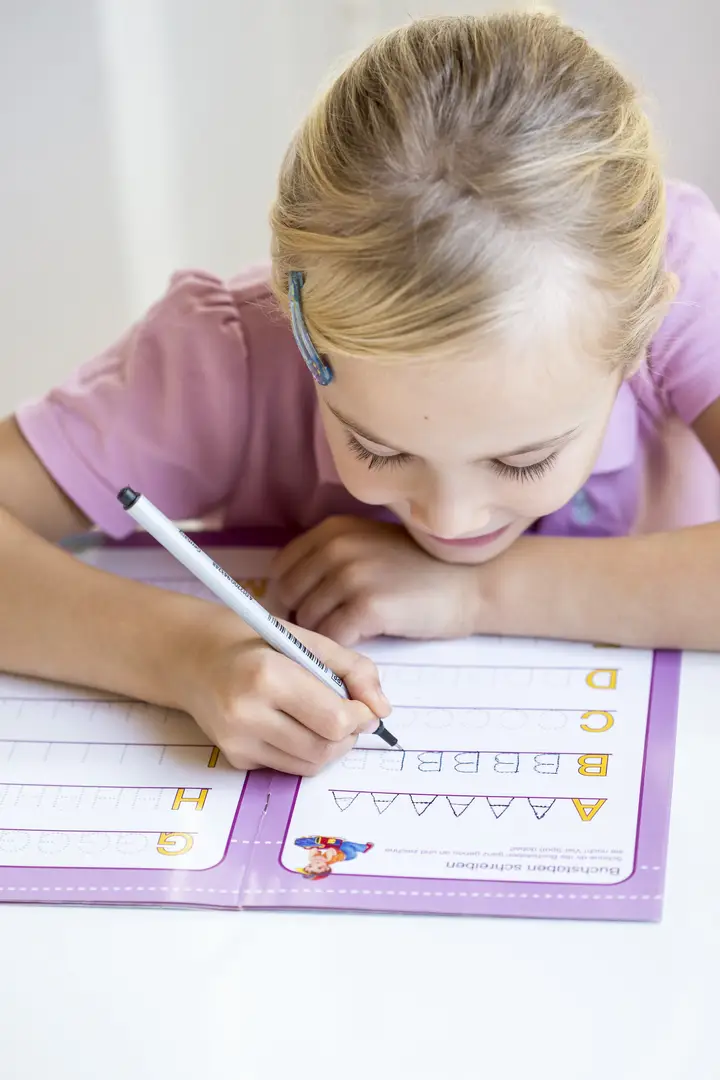 Young child practising handwriting in a workbook