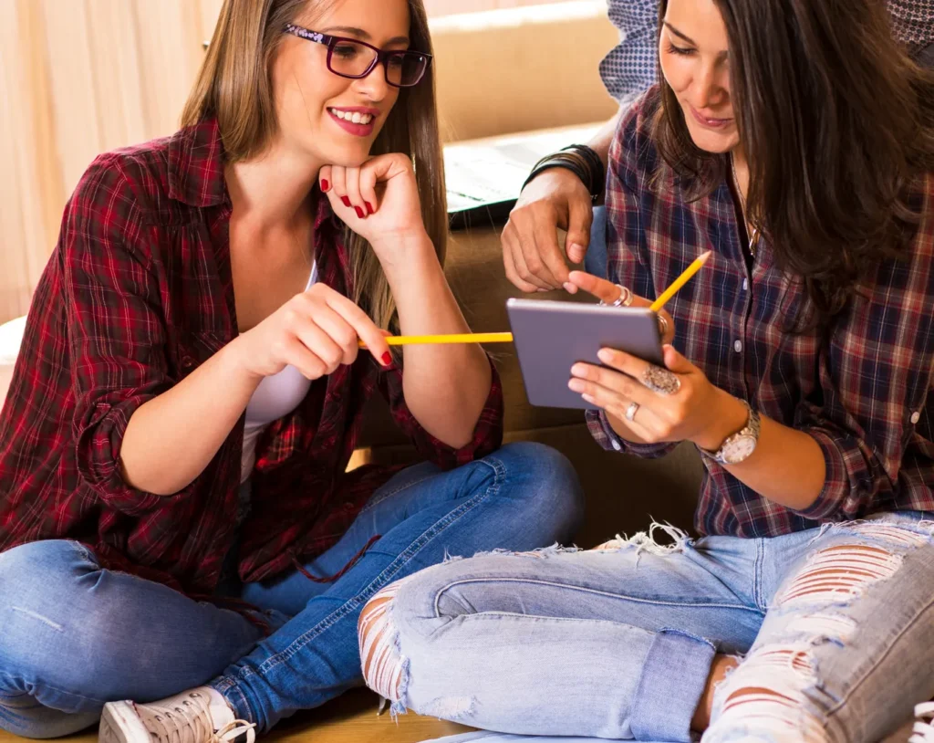 Two sixth-form students revising together with a tablet and notes