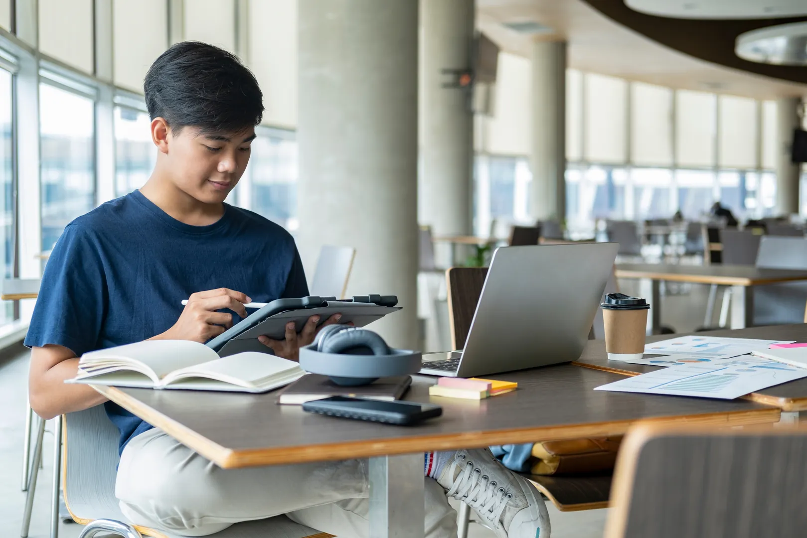 Sixth-form student studying with a laptop and notes